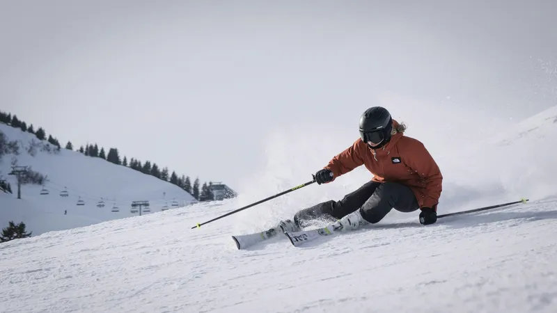 Skifahrer in roter Jacke fährt dynamisch eine Piste hinunter.