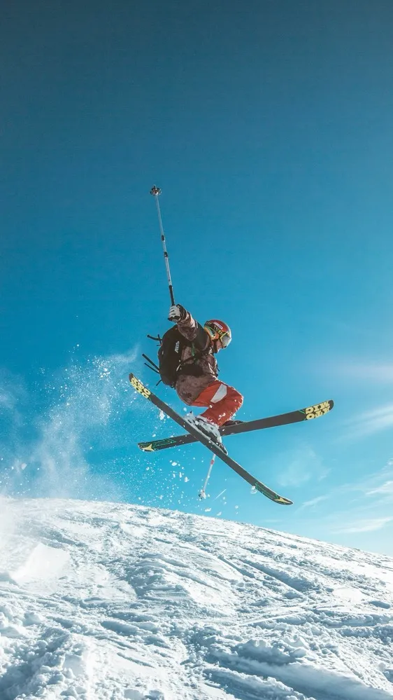 Skifahrer springt dynamisch in die Luft über schneebedeckten Hang.